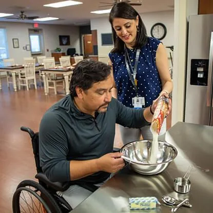 A practitioner supporting a wheelchair user to prepare food in a kitchen